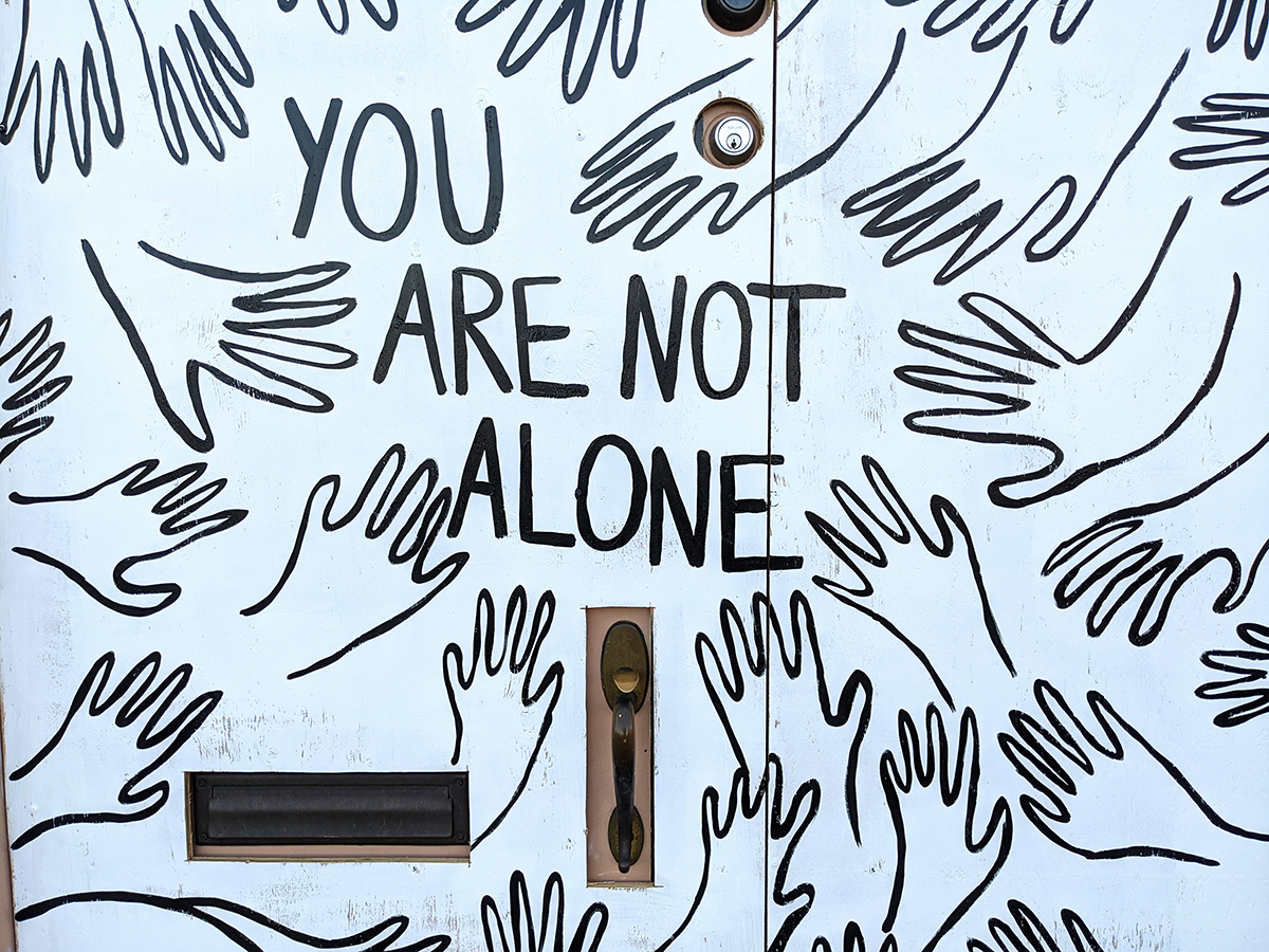 Multiple line drawing of hands with the words "you are not alone"